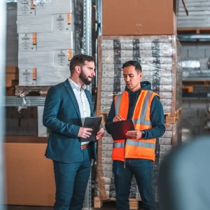 Inspector analyzing products at factor for conformity assessment that complies with ISO 17021-1:2015.