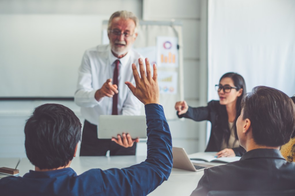 Businessman raising hand for asking speaker for question and answer concept in meeting room of diversity business people