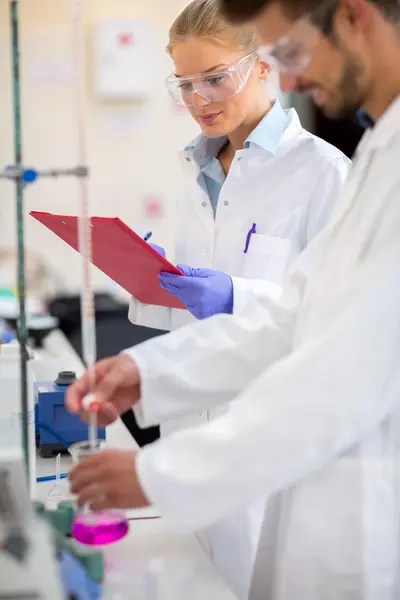 Researchers in a laboratory taking notes.